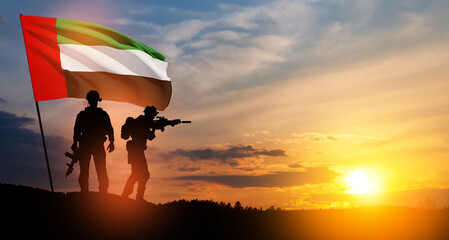 Silhouettes of soldiers with the flag of UAE against sunset or sunrise. Concept of national holidays.