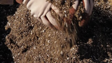 Gardening. Closeup view of a gardener hands with gloves, mixing soil made of black earth, perlite and sand.