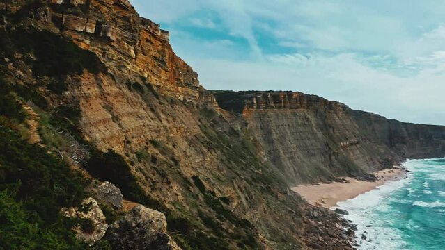 Drone is panning of the  rocky Atlantic ocean coastline, Portugal, in summer sunny day. Beautiful aerial view natural landscape with ocean rocky shore.  Scenic tourist travel destination. No people.
