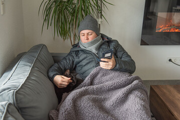 Fototapeta premium Woman sitting at home with jacket freezing saves energy