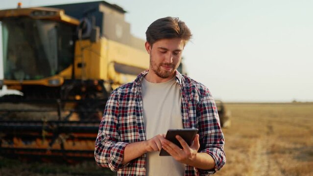 Agronomist uses modern technologies in agriculture, yield map apps at wheat field. Precision smart farming. Farmer use digital tablet for combine harvester guidance and control with automation system.
