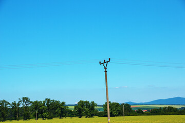 Electric pole power lines outgoing electric wires againts on cloud blue sky.
