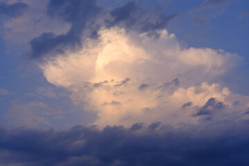 Naklejka na ściany i meble Beautifully lit cloud in the evening blue sky