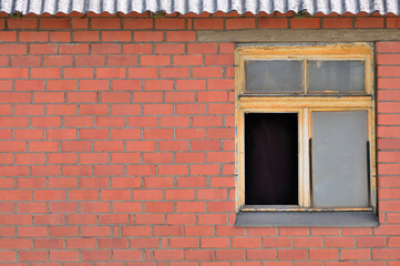 Old aged shed broken window glass, red bricks hut wall background, weathered grungy rusty dirty damaged wooden frame, textured large detailed horizontal shack backdrop, blank empty copy space closeup