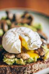 Healthy breakfast from poached egg, smashed avocado, grilled mushrooms on sourdough bread toast, selective focus, shallow DoF