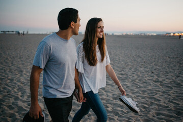 A man and his girlfriend are strolling on a sandy beach at twilight in Spain.