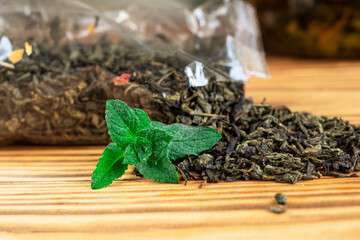 selective focus. great tea loose leaf. Scattered dried, loose green tea with fresh mint on wooden...