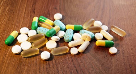 Pills and capsules lie on a wooden table. View from above. The concept of healthcare and medicine.