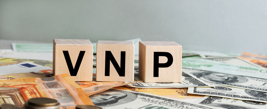 VNP inscription on the texture of wooden cubes. Wooden cubes on the background of banknotes. An inscription on a financial, business or economic theme.