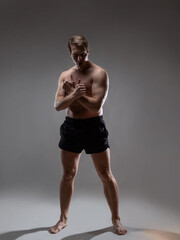 Obraz premium young muscular man in an expressive pose, artistic pose of the hero with outstretched arms. Beautiful muscles. extraordinary athletic body. Portrait on a gray background