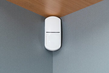security alarm motion sensor on gray wall.