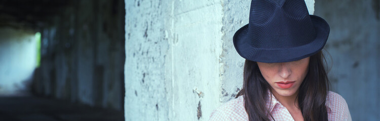 Fashionable girl with hat on her head standing in abandoned building