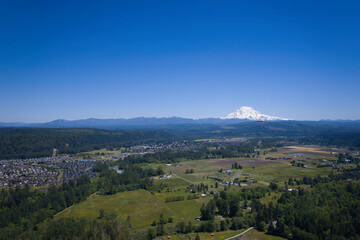 An aerial view of Puyallup, Washington with Mt. Rainier covered in snow under a clear blue sky in...