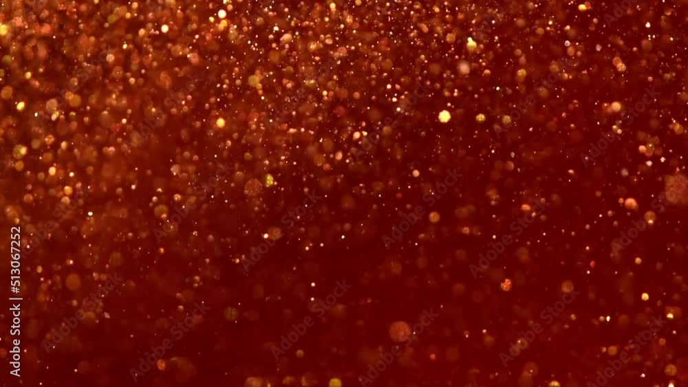Wall mural Smoothly Falling Golden Dust Particles in a red fluid. Gold particles and bokeh move slowly in red liquid. Abstract moving relaxing background.