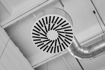 Ventilation and air conditioning system, close-up. Ventilation pipes and hoods in industrial or commercial premises, under the ceiling. Monochrome black and white image.