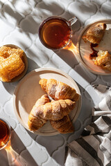Breakfast concept top view with croissants, two tea cups, honey and beautiful shadows in hard sunlight