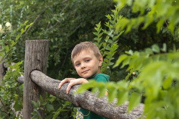 a five-year old child sits on a wooden fence in the village