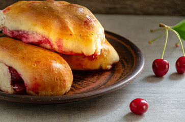 Homemade pies with cherries on a clay plate. Homemade baking.