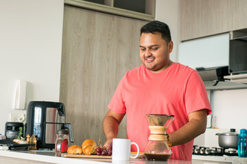 Fototapeta na wymiar Lifestyle: Man dieting to lose weight and have better health. Correct problems of obesity and sedentary lifestyle. Latin American young adult in the kitchen of his house preparing a healthy breakfast