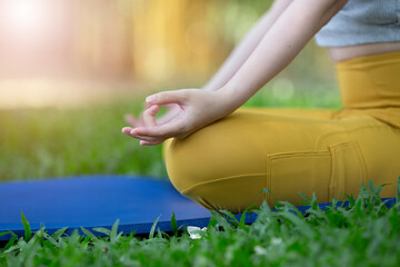 Close up of woman practice yoga meditation exercise in park, beautiful female sitting on mat for relaxed yoga posture in the morning , exercise at park, mental health care,healthy and sport