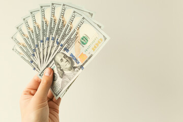 A man holds in his hand a thousand dollars in bills of one hundred dollars on a white background.