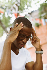 Close-up of exhausted, stressed multiracial dark skin man in glasses keeping hands on head,...