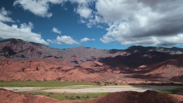 Time lapse in Quebrada de las Conchas in Cafayate, Salta, Argentina. View of the valley, desert, red sandstone and rocky mountains and white clouds passing by, creating shadows in the landscape.