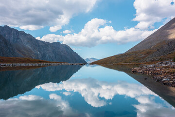 Tranquil autumn landscape with clouds reflection on smooth mirror surface of mountain lake in high...