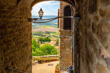 View of the Tuscan countryside through a medieval arched stone doorway from a tunnel in the hilltop...