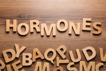 Word Hormones made of letters on wooden table, flat lay