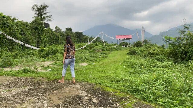 Rear view of Happy young Indian girl walking through mountain roads and visiting the traditional tomb of Buddhist at hill top.