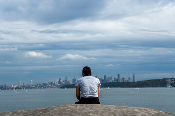 A female hiker sitting at the edge of the bay, facing skyline and the sea, Watsons Bay to Hornby...