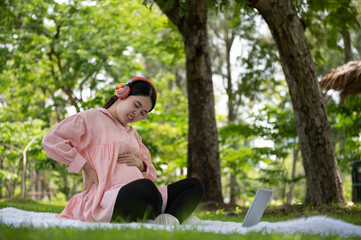Fototapeta premium Pregnant woman having abdominal and back aches in the garden