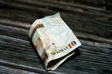 Folded Saudi Arabia money of 10 SAR ten riyals isolated on wooden background, Crumpled 10 Saudi...