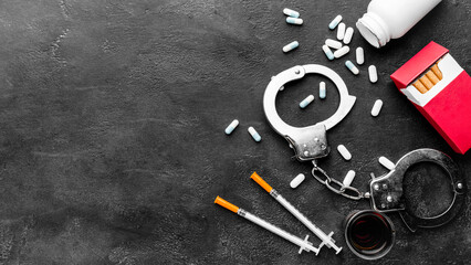 cigarettes, handcuffs in one picture. with an abstract black background.