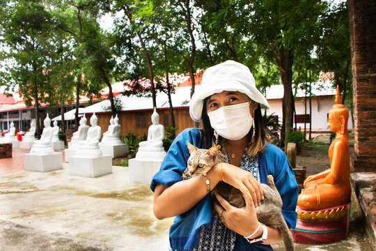 Thai women traveler people travel visit and respect praying blessing holy mystery buddha worship of Wat Phra Kaew temple and carry hold little cat at Chainat city on May 27, 2020 in Chai Nat, Thailand
