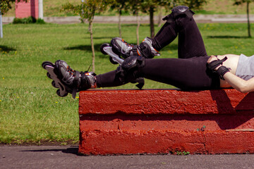 Sporty young woman stretching and resting after skating in a park on a sunny day