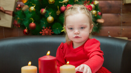 A girl looks at the burning candles Christmas evening with interest and curiosity.