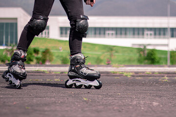 macro photography of some inline skates, and a woman using them on the asphalt on a sunny day