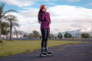 young sporty woman practicing inline skating in an urban setting. Prepare sportwatch and headphones