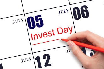 Hand drawing red line and writing the text Invest Day on calendar date July 5. Business and financial concept.