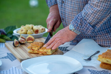 Elderly man spread fig jam on slices of bread outdoor.