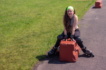 Sporty young woman stretching and resting after skating in a park on a sunny day