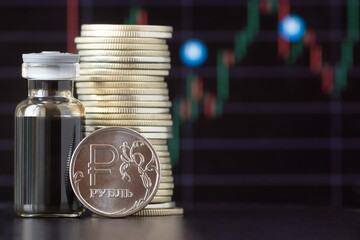 Ruble coins and a bottle of crude oil against the background of a price chart. The inscription on the coin - ruble