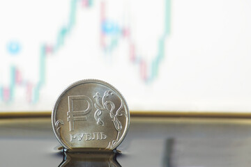 A coin with a sign and an inscription ruble in crude oil against the background of a price change chart