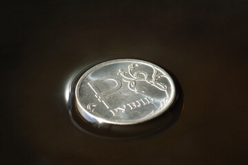 Coin with ruble sign on crude oil surface. Sale of natural resources. Inscription - ruble