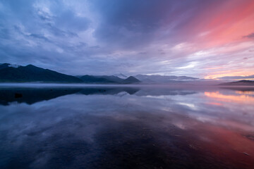 Fototapeta na wymiar 雲を染める幻想的な日没の空を湖面に映す黄昏の湖。日本の北海道の屈斜路湖。