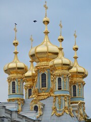Fototapeta na wymiar The cross atop the golden-yellow dome of a Russian building.