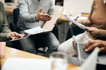 Close up of entrepreneurs having briefing during business meeting in office.