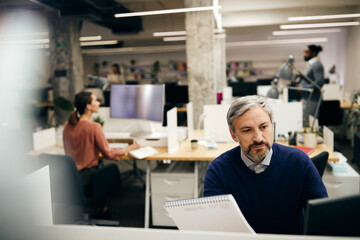 Mature businessman working on desktop PC at corporate office.